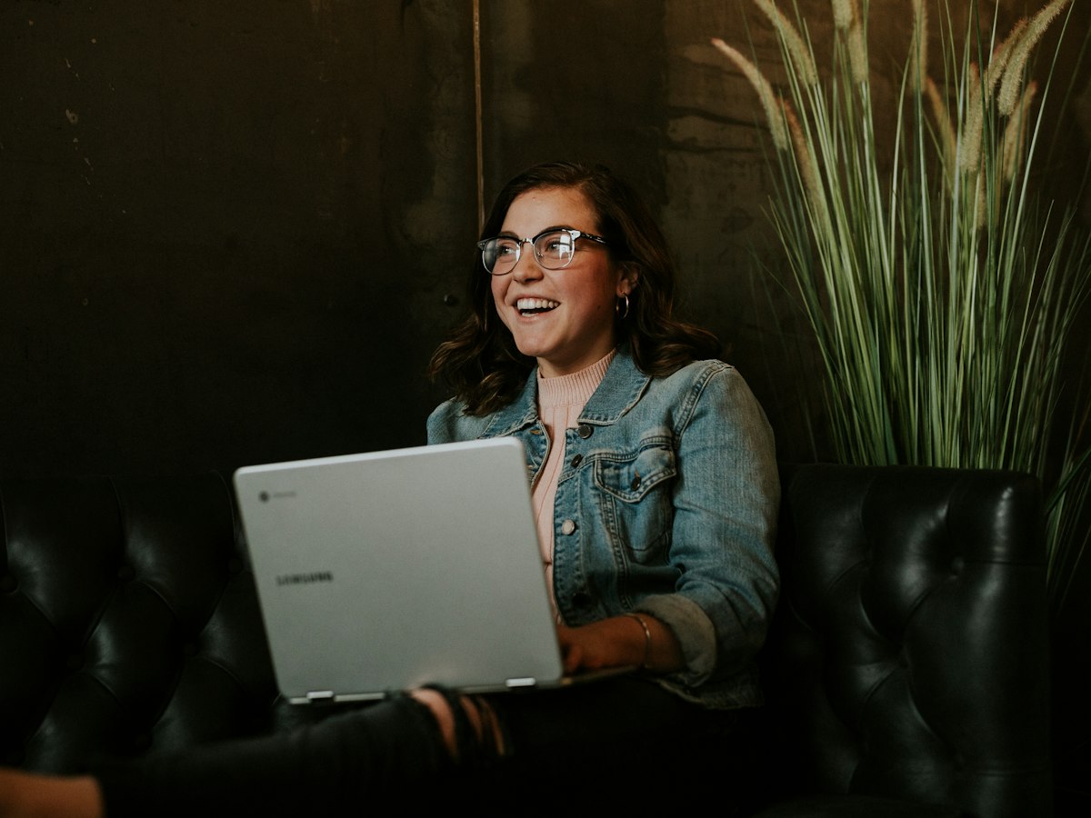 Mujer sonriendo con su laptop después de organizar sus deudas